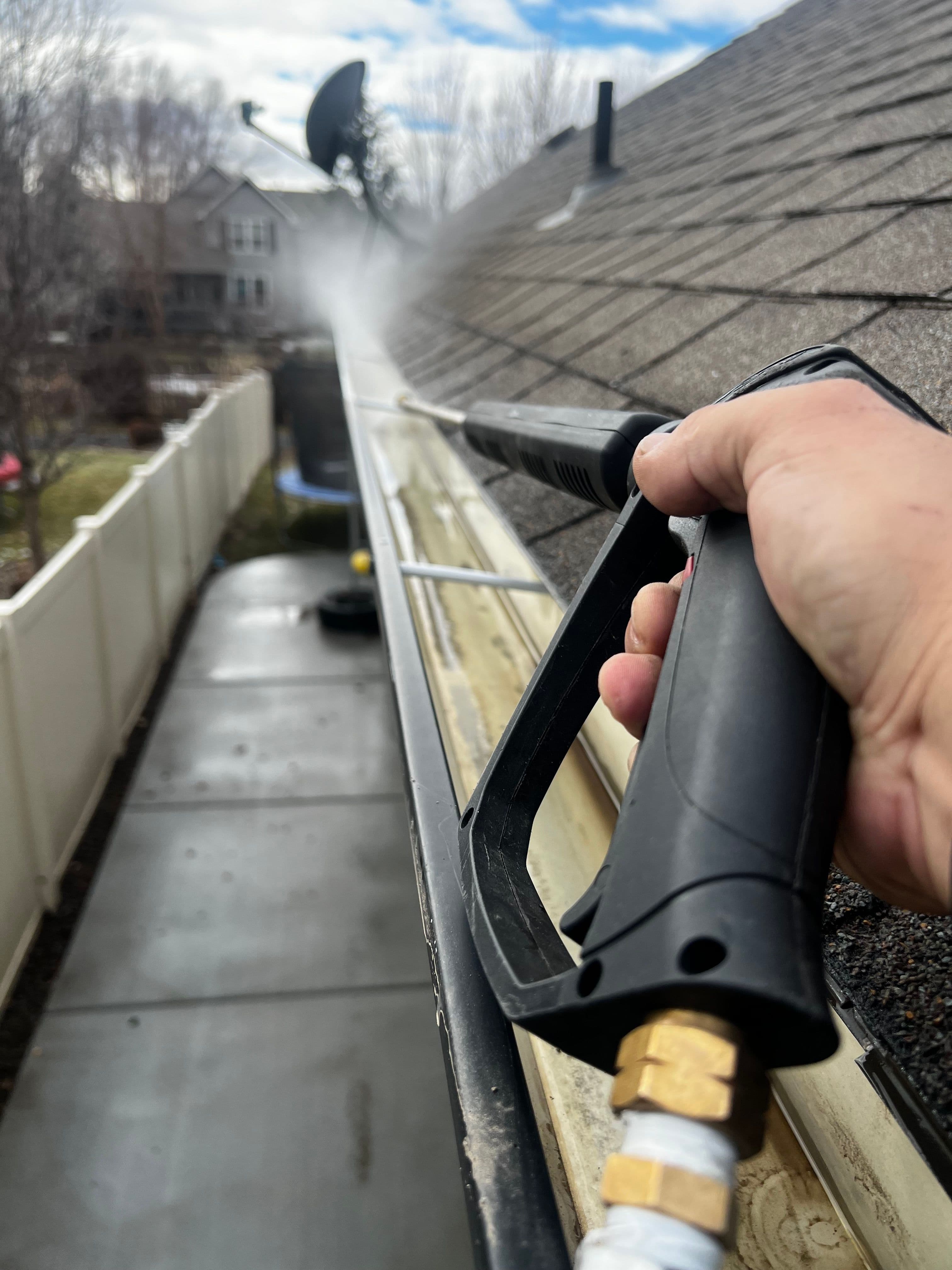 Super Shine Services technician spraying out a gutter along a roofline
