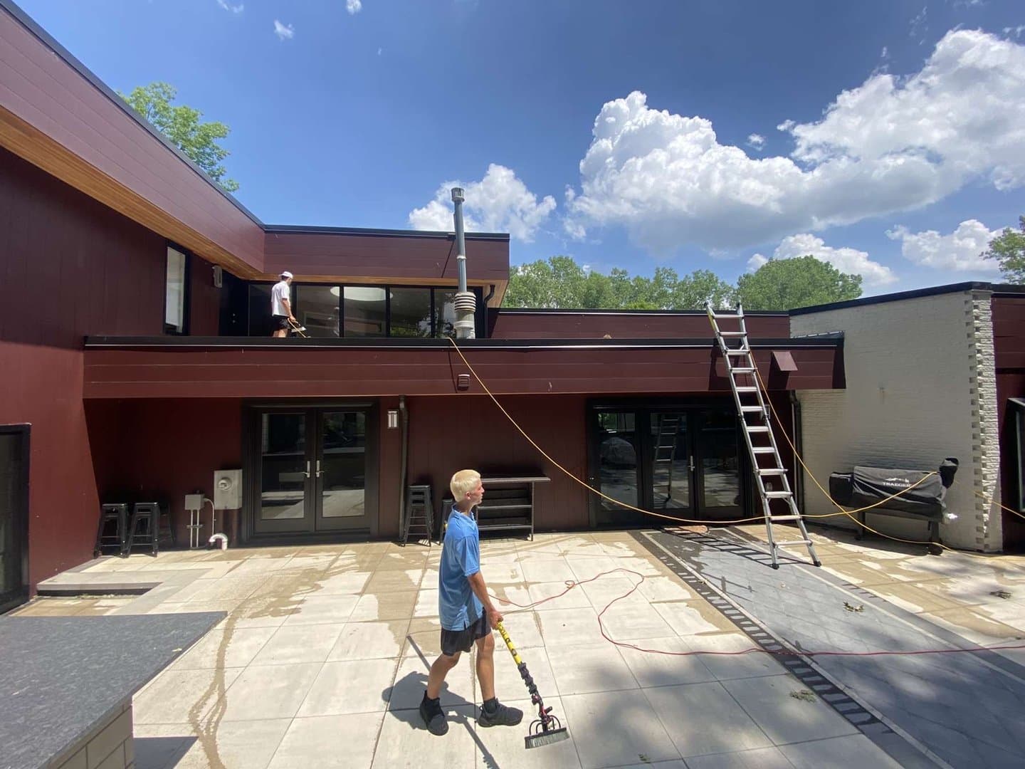 Super Shine Services technician cleaning the exterior of a white colonial home