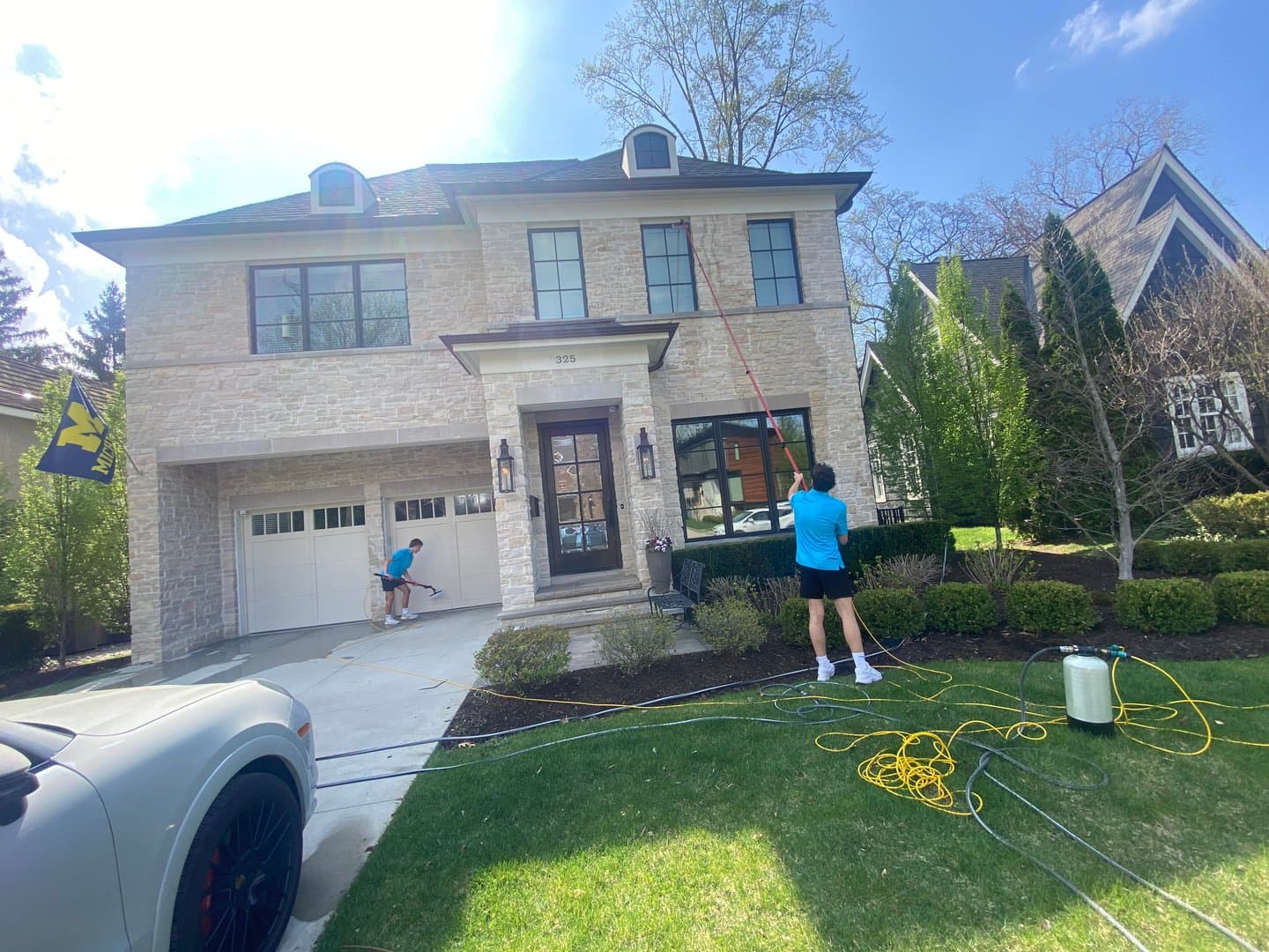 Super Shine Services technician cleaning windows and gutters on a white colonial home