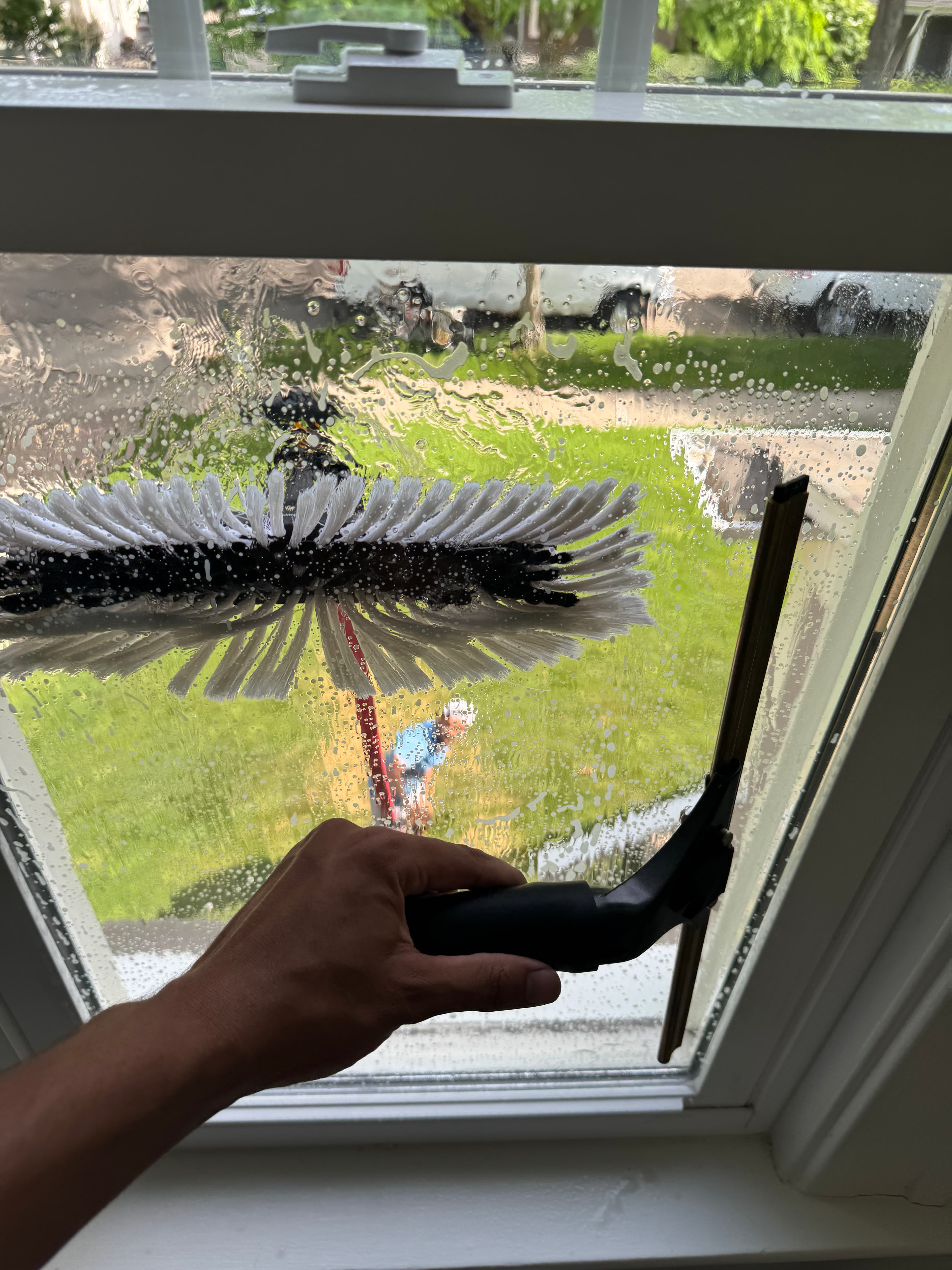 Super Shine Services technician squeegeeing a soapy window mid-clean